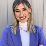 Eine lächelnde Frau in einem lila Blazer posiert mit dem Einfachmarketing-Team.