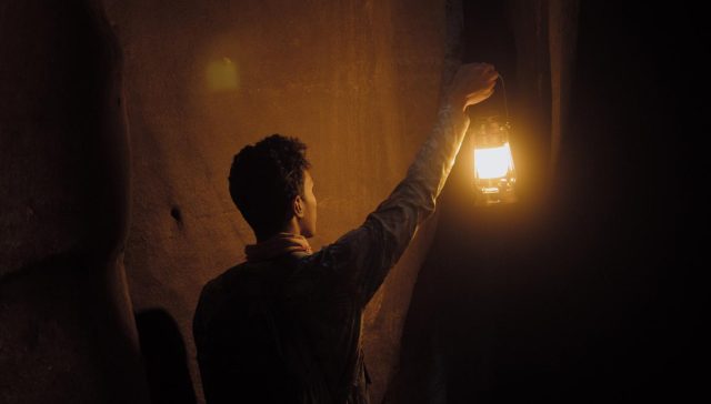Ein visuell fesselndes Bild eines Mannes, der in einem dunklen Raum nach einem Licht greift, stellt die Kunst des Geschichtenerzählens perfekt dar.