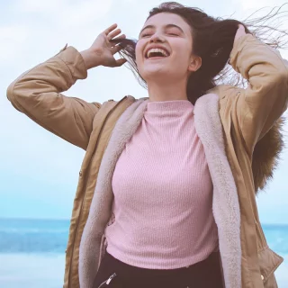 Eine Influencerin posiert am Strand, während ihr Haar anmutig im Wind weht.