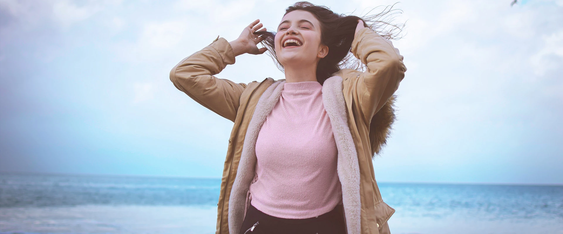 Eine Influencerin posiert am Strand, während ihr Haar anmutig im Wind weht.