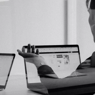 Ein Schwarz-Weiß-Foto, das zwei Personen zeigt, die mit Laptops Wachstumsmarketing-Aufgaben erledigen.