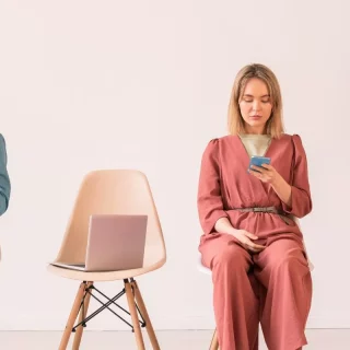 Eine Gruppe von Menschen, die auf Stühlen sitzen und mit ihren Telefonen auf Instagram surfen und gesponserte Werbung ansehen.