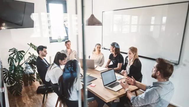 Eine Gruppe von Performance Marketing Fachleuten trifft sich an einem Konferenztisch in einem modernen Büro.