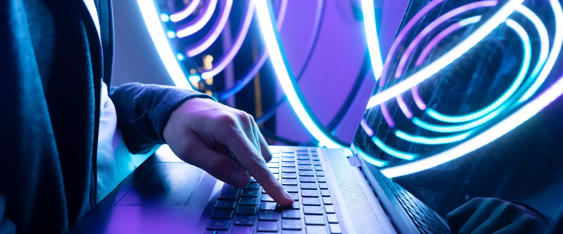 Eine Person, die eine Tastatur mit leuchtend blauer und violetter LED-Beleuchtung im Hintergrund verwendet.