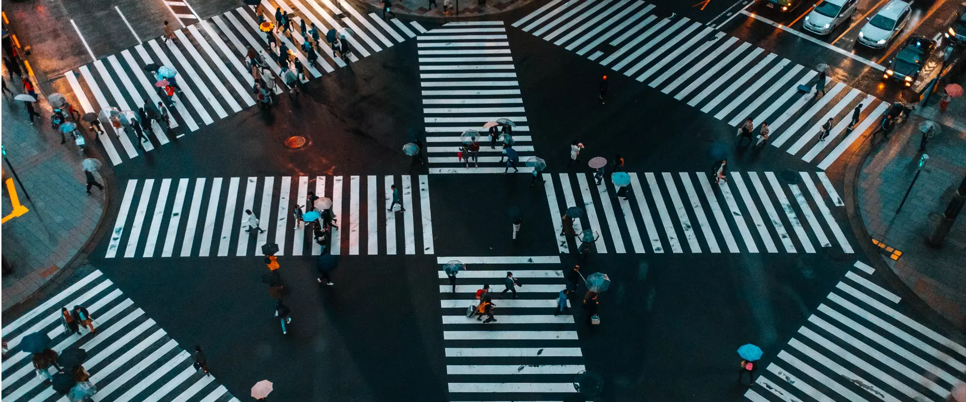 Luftaufnahme eines belebten Fußgängerübergangs mit Menschen, die die Straße in verschiedene Richtungen überqueren, was ein perfektes Szenario für die Zielgruppenanalyse darstellt.